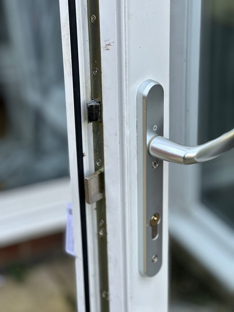 Satin handle and multipoint strip on a white uPVC French door in Radford