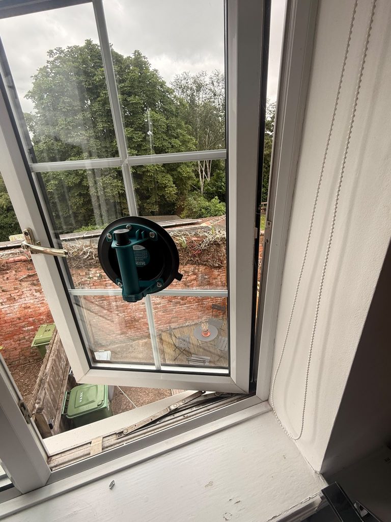 Georgian-bar window sash supported by a suction cup during hinge repair in Radcliffe-on-Trent