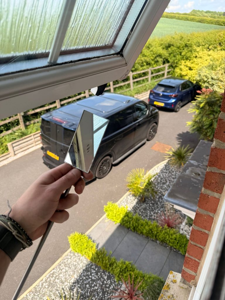 Locksmith inspecting a failed uPVC window locking mechanism with a mirror during a window lock repair in Nottingham
